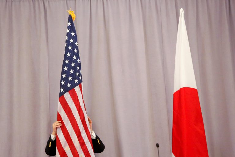 A worker adjusts the U.S. flag before Japanese Prime Minister Shinzo Abe addresses media following a meeting with President-elect Donald Trump in Manhattan, New York, U.S.