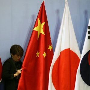 An officer adjusts China's national flag before the ASEAN Plus Three (APT) Summit in Singapore