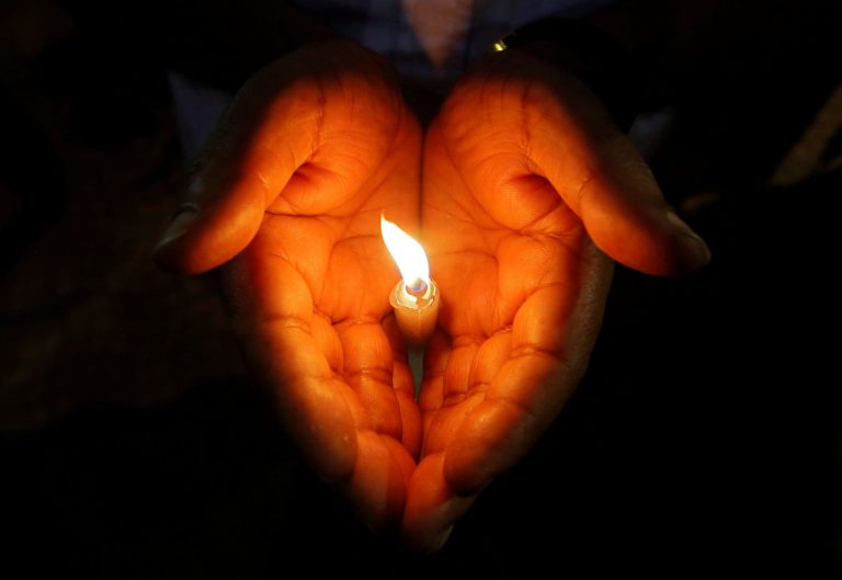 A man holds a candle during a vigil to show solidarity with the victims of Sri Lanka's serial bomb blasts, inside a college in Kolkata