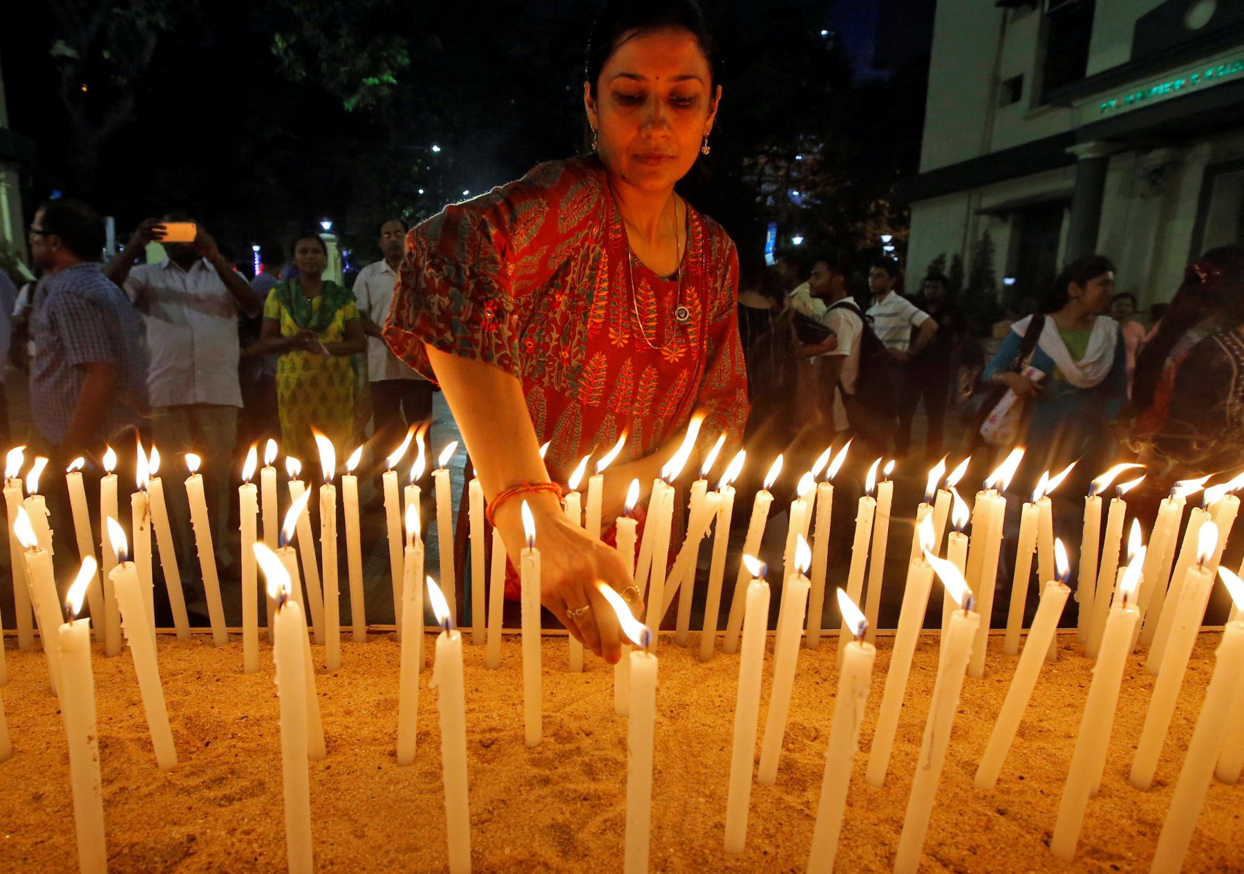 A woman lights a candle during a vigil to show solidarity with the ...