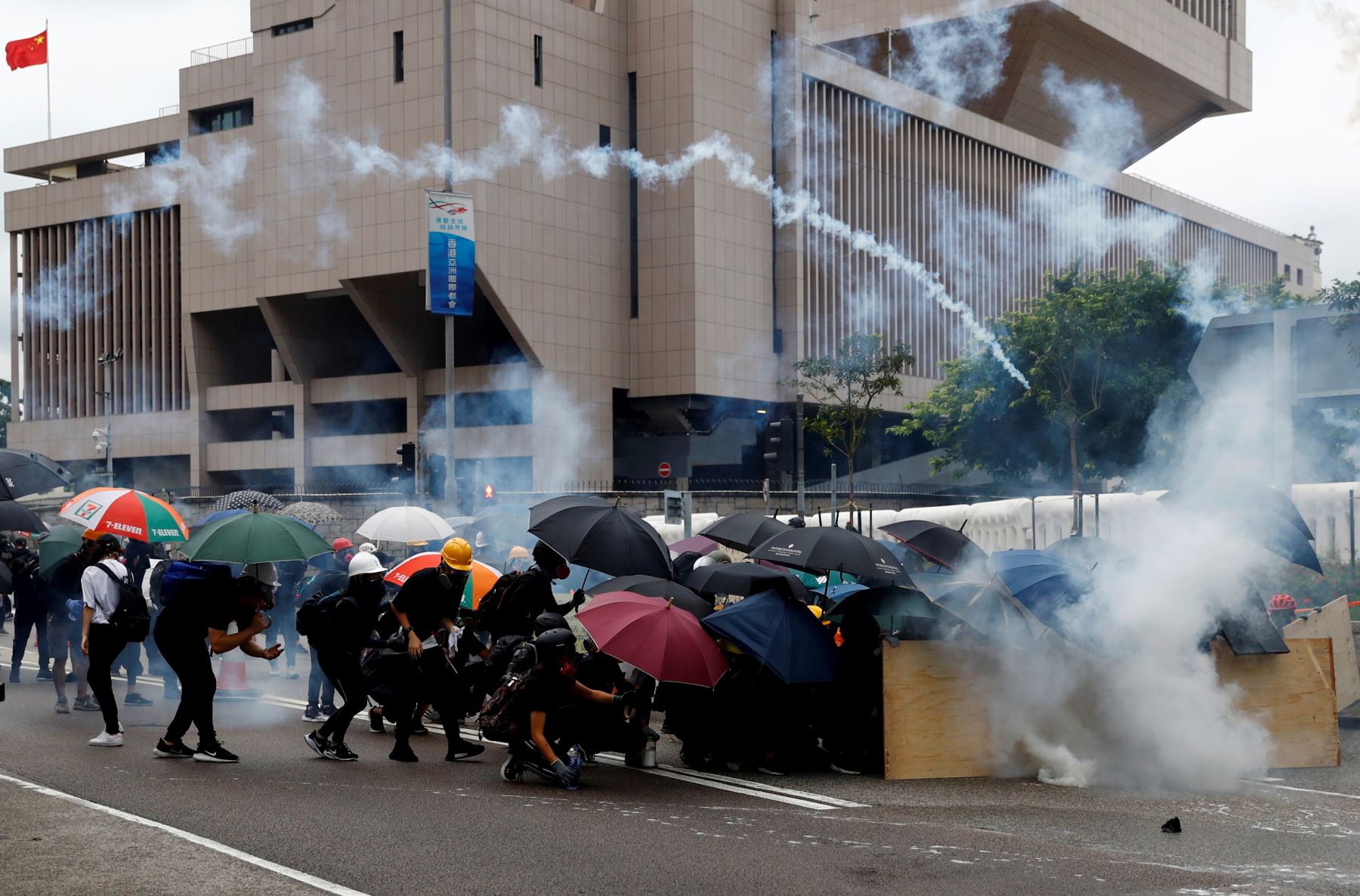 Demonstrators take cover as police fires tear gas during a protest in Hong Kong