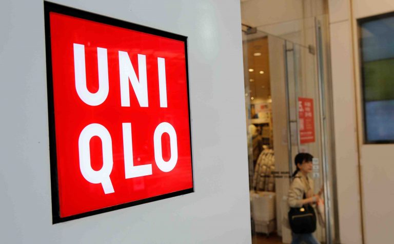 A woman walks past the logo of Uniqlo at Myeongdong shopping district in Seoul