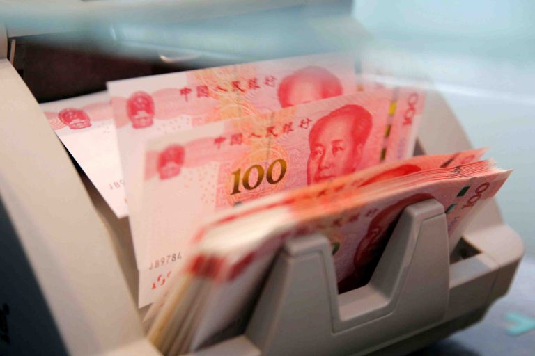 FILE PHOTO: Chinese 100 yuan banknotes are seen in a counting machine while a clerk counts them at a branch of a commercial bank in Beijing